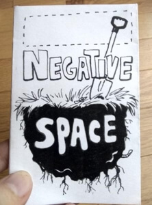 Minizine cover of Negative Space. Cover illustration: a shovel stuck into a floating chunk of dirt and grass.