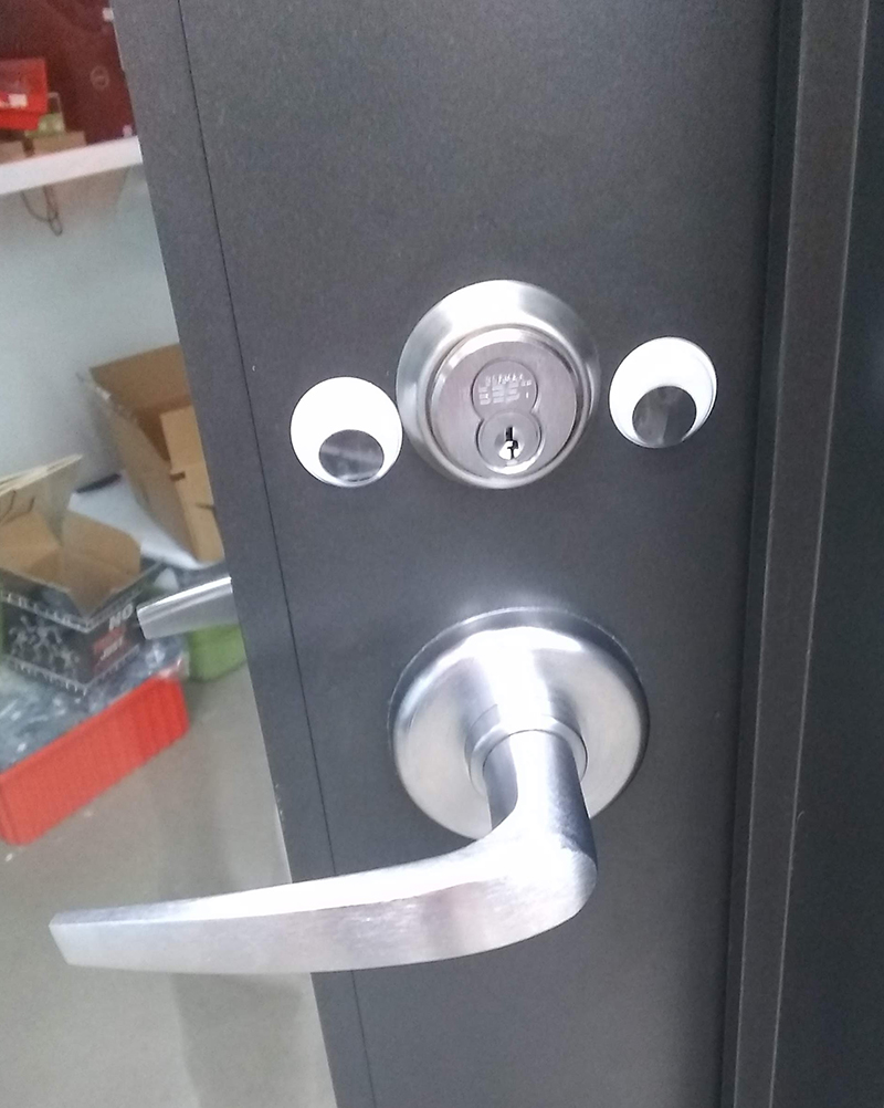 Googly eyes on a door above the handle. The handle looks like a mouth or nose.