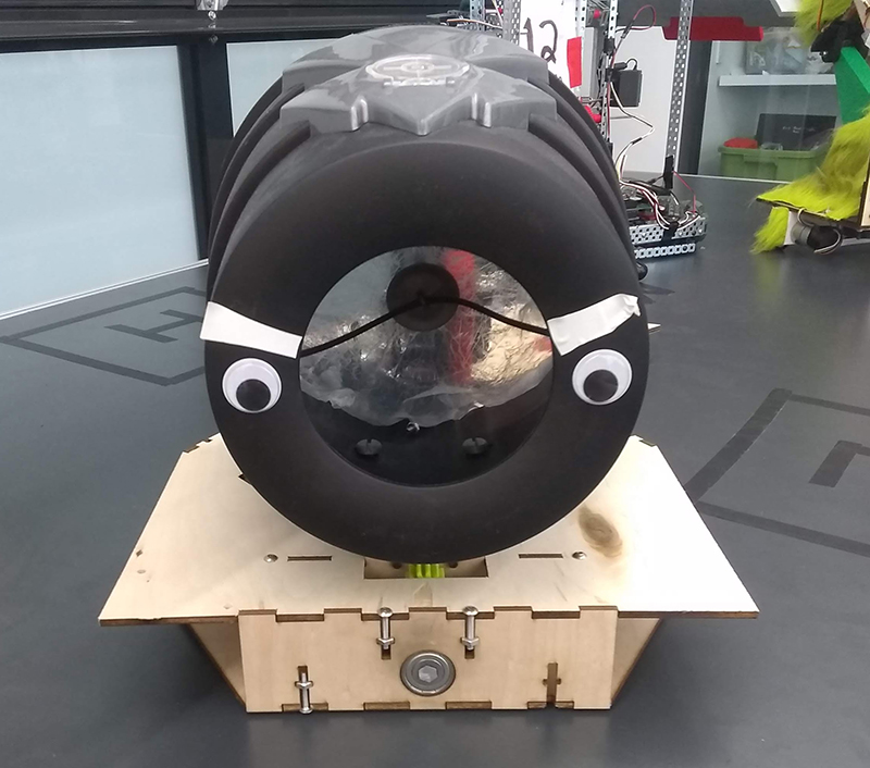 Googly eyes with angry brows on a handheld air cannon.