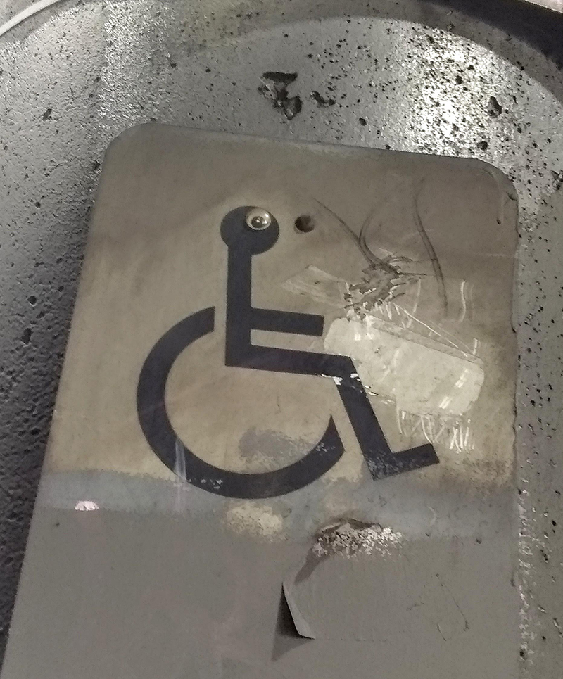Googly eye on a disabled sign, giving the stick figure in the wheelchair a surprised look.