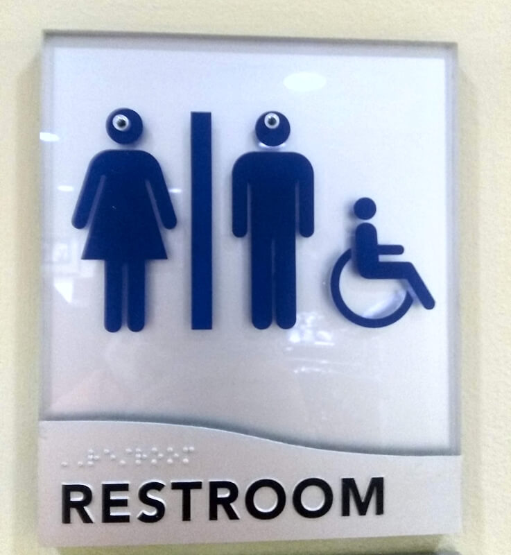 Googly eyes on a restroom sign.