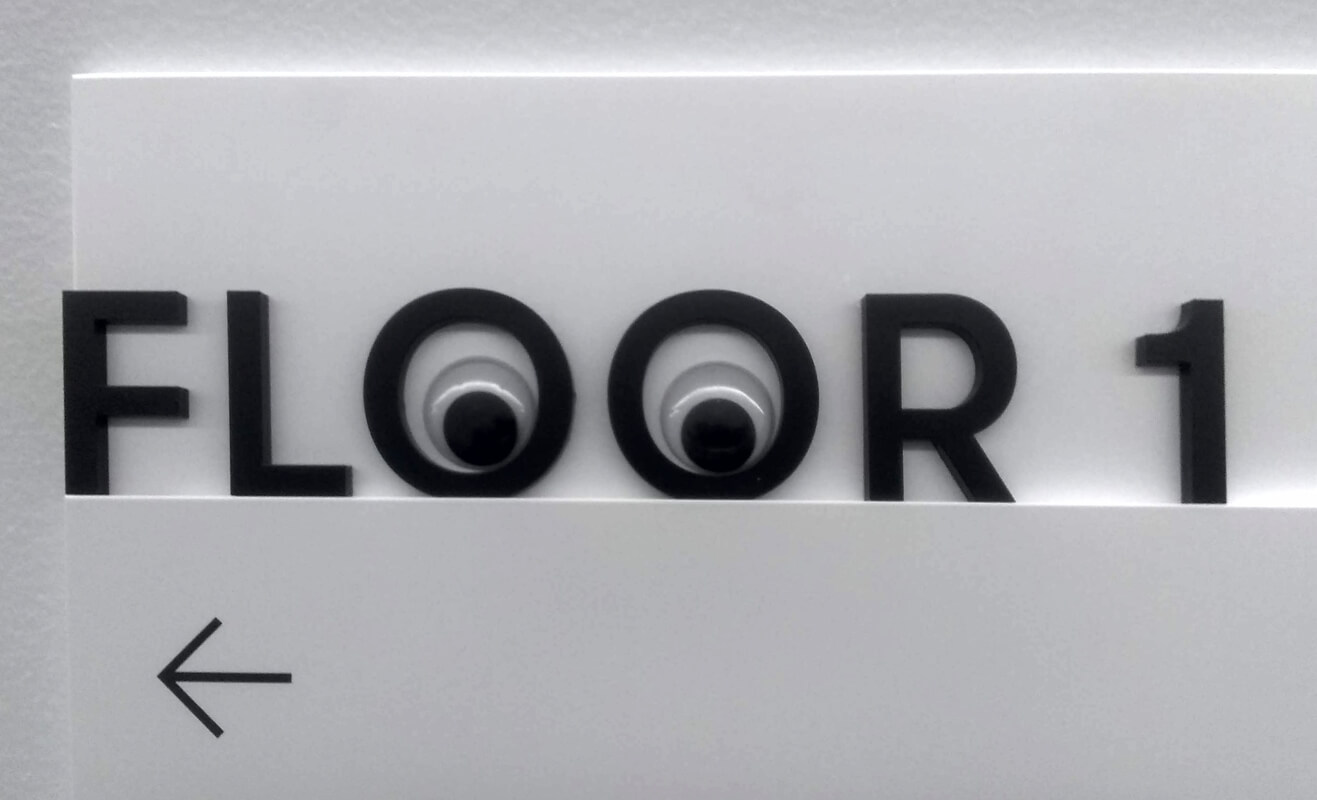Googly eyes in the double O's of a sign that says Floor One.